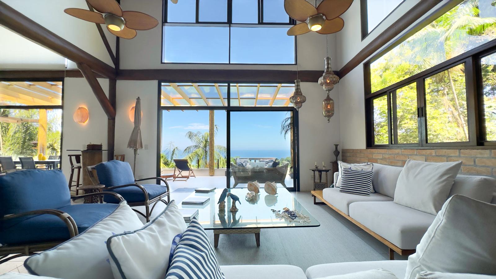 Sala principal da Villa 231 com vista para o mar e arquitetura em toras de madeira aparente.