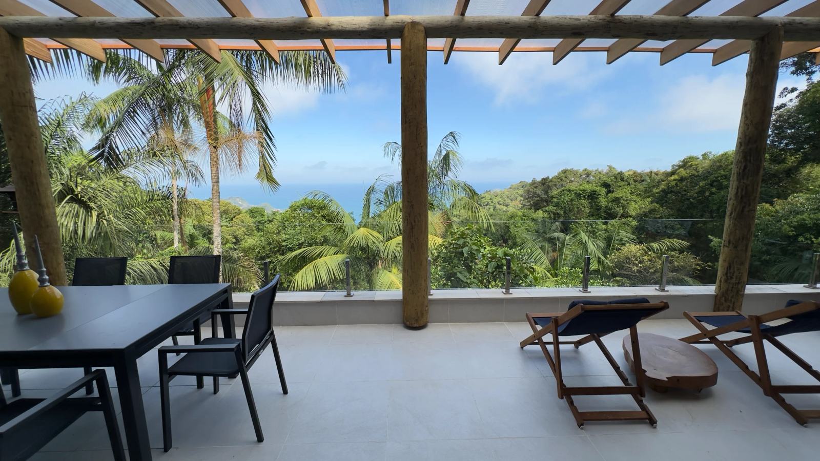 Varanda da Villa 231 com mesa de jantar e vista panorâmica para o mar no Condomínio Iporanga, Guarujá.