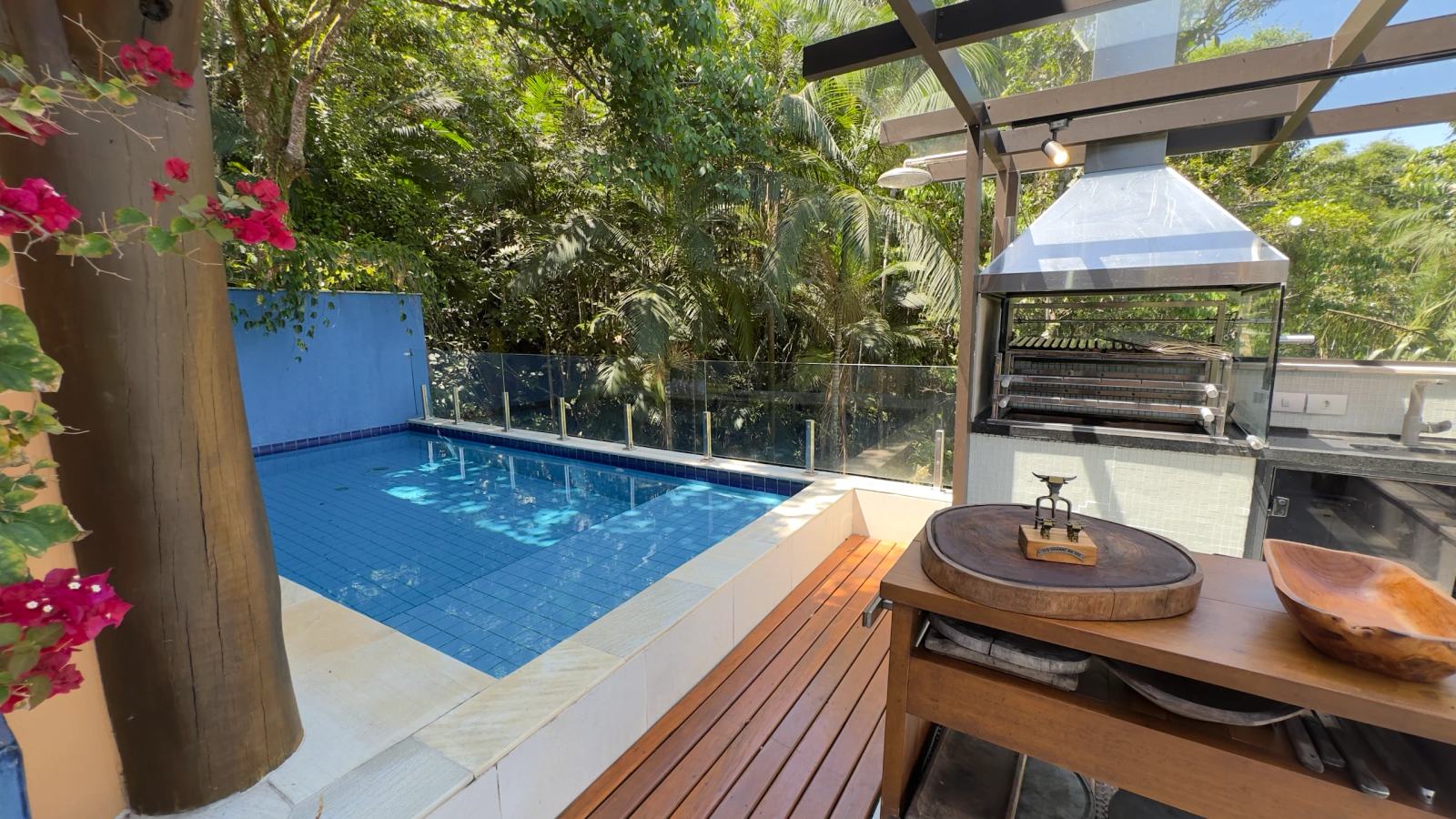 Piscina aquecida da Villa 231 com deck de madeira e churrasqueira gourmet.